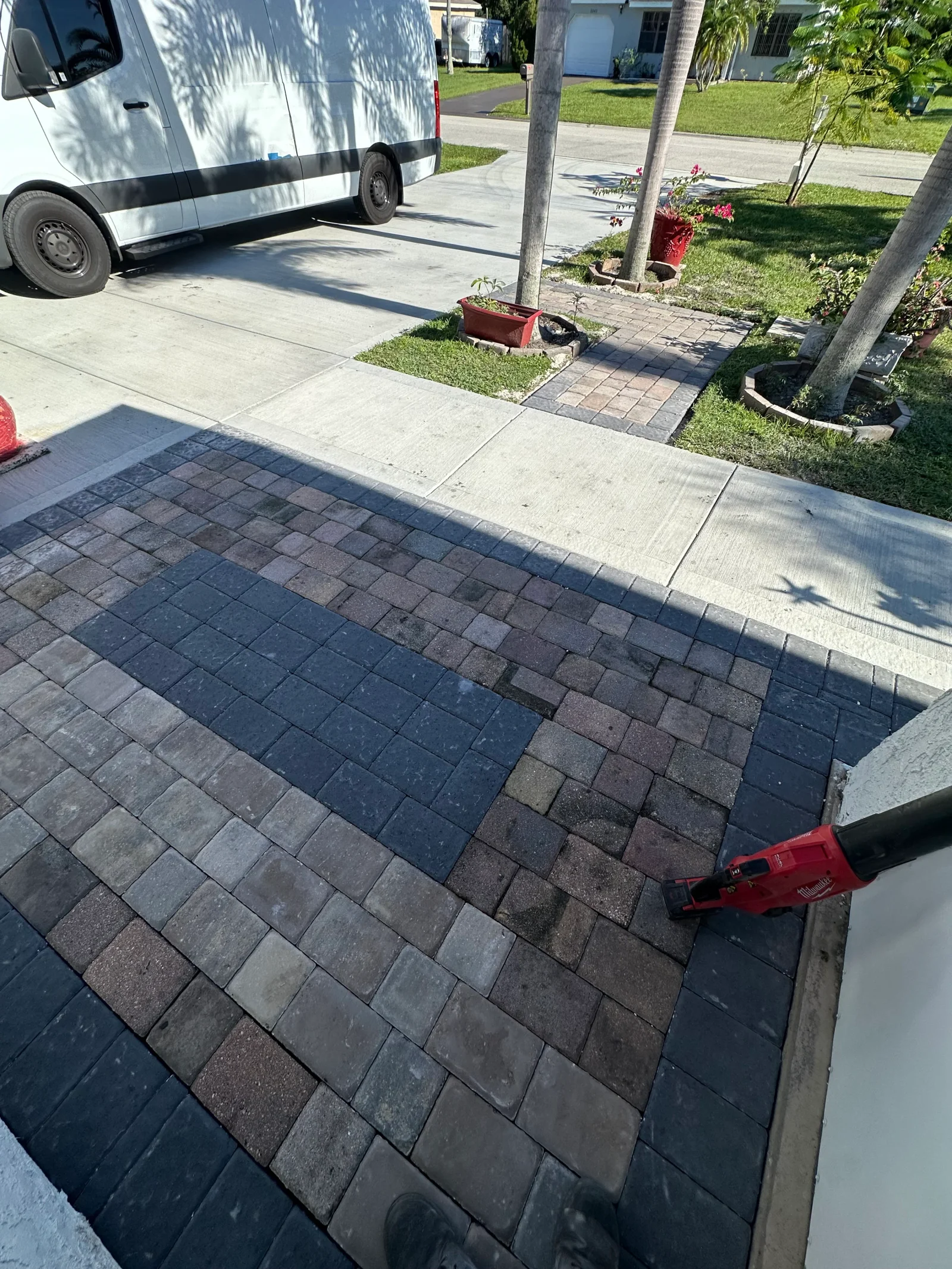 Multi-tone gray and brown interlocking concrete pavers with dark border and inset panel on a driveway